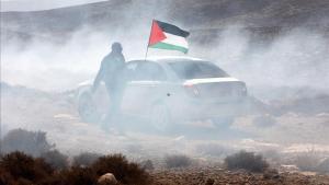 Un hombre ondea la bandera palestina entre gas lacrimogeno en el pueblo cisjordano de Shiyoukh.