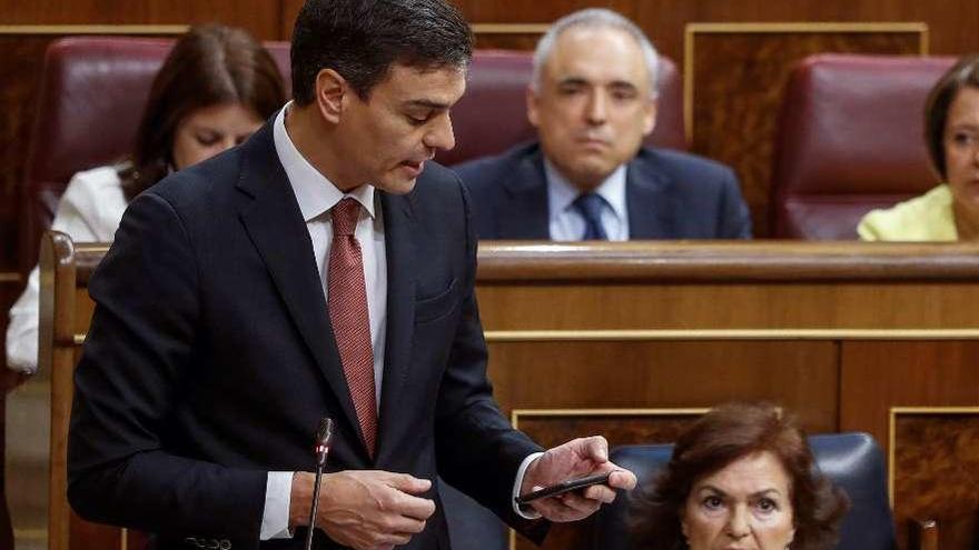 Sánchez consulta unos datos en su móvil durante la sesión de control al Gobierno en el Congreso.