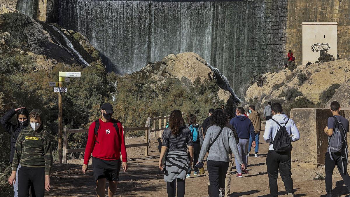 Grupos de senderistas que caminan junto a la presa del Pantano de Elche durante este invierno. | ANTONIO AMORÓS