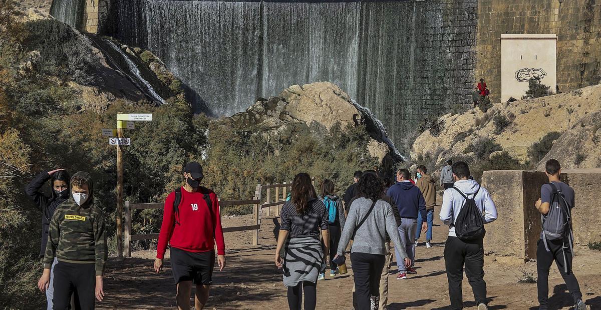Grupos de senderistas que caminan junto a la presa del Pantano de Elche durante este invierno. | ANTONIO AMORÓS