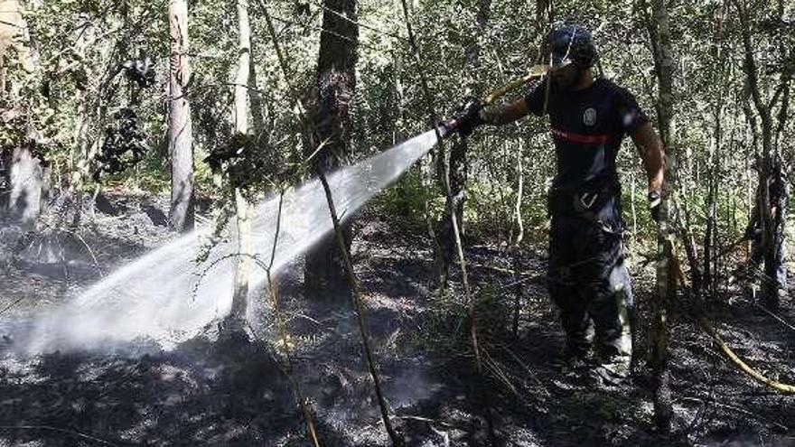 Un bombero refresca la zona tras controlar el incendio.  // R. Grobas