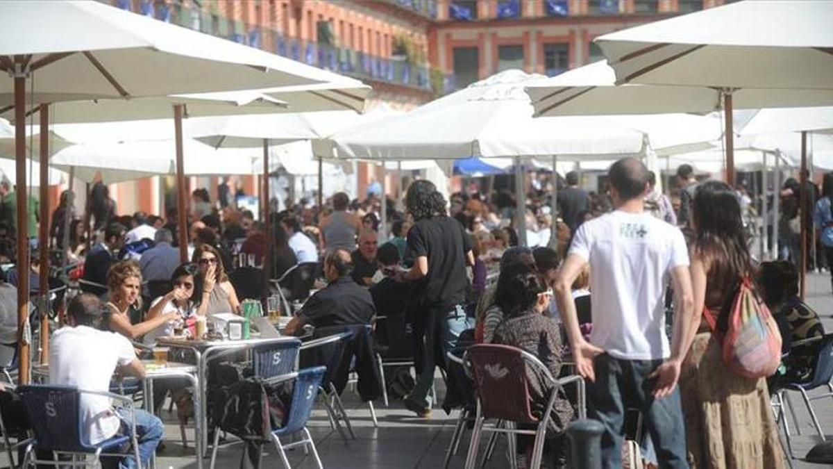 Personas consumiendo en una terraza de La Corredera.