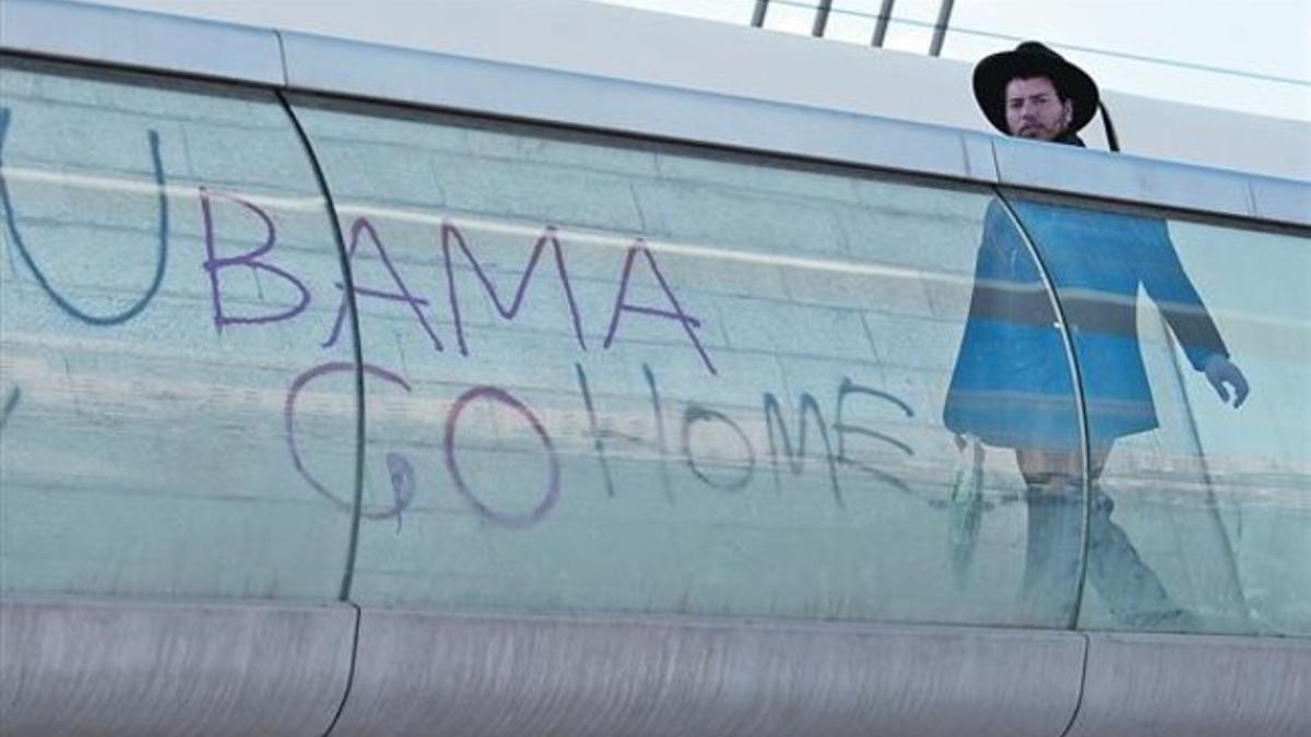 Un hombre pasa junto una pintada en contra de la visita de Barack Obama, ayer.