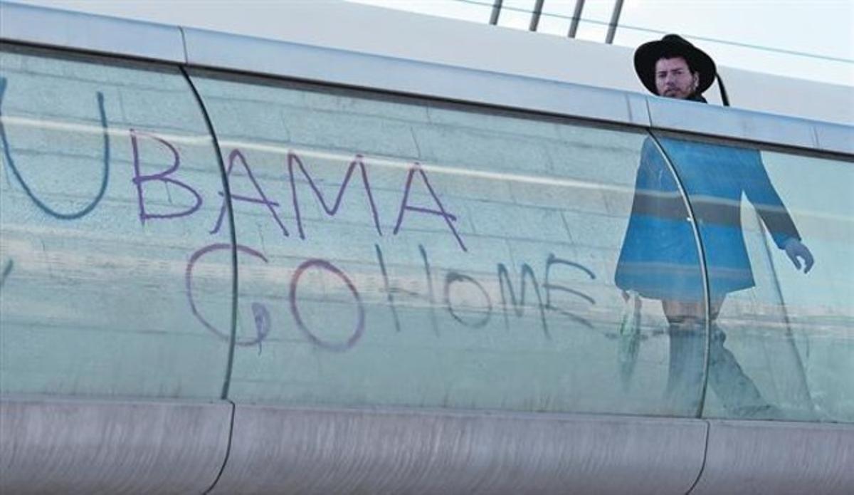 Un home passa davant d’una pintada en contra de la visita de Barack Obama, ahir.