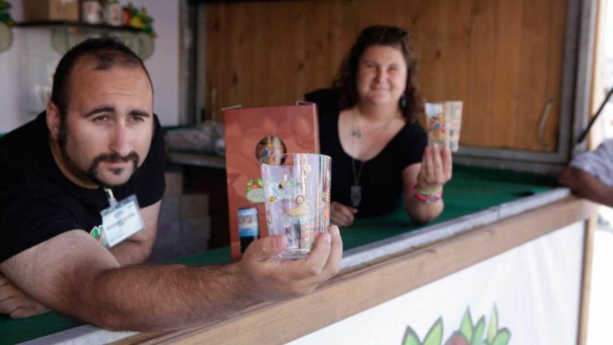 Dos de los trabajadores del Festival de la Sidra muestran los vasos que se vendieron para la recaudación.