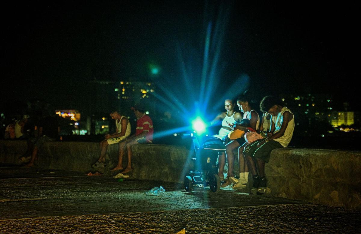 People gather at the Malecon waterfront during a blackout in Havana on March 16, 2026. Cuba suffered a widespread power cut on March 16, 2026, according to the national electricity company, against the backdrop of a severe crisis on the island caused by the US energy blockade. (Photo by ADALBERTO ROQUE / AFP)