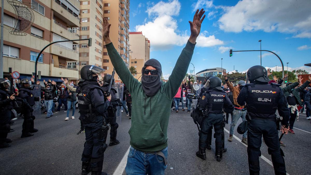 Un manifestant alça els braços rodejat de policies a Cadis