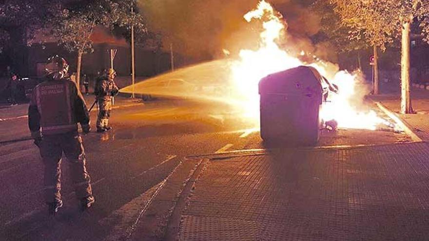 Los bomberos arrojan agua sobre varios contenedores en llamas