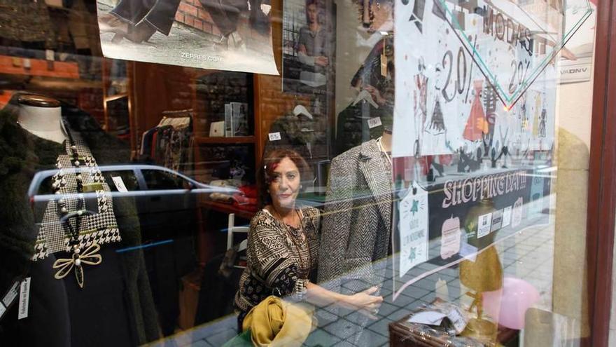 Consuelo Joglar coloca el escaparate de su tienda, con un cartel anunciando el &quot;Shopping Day&quot; en primer término.