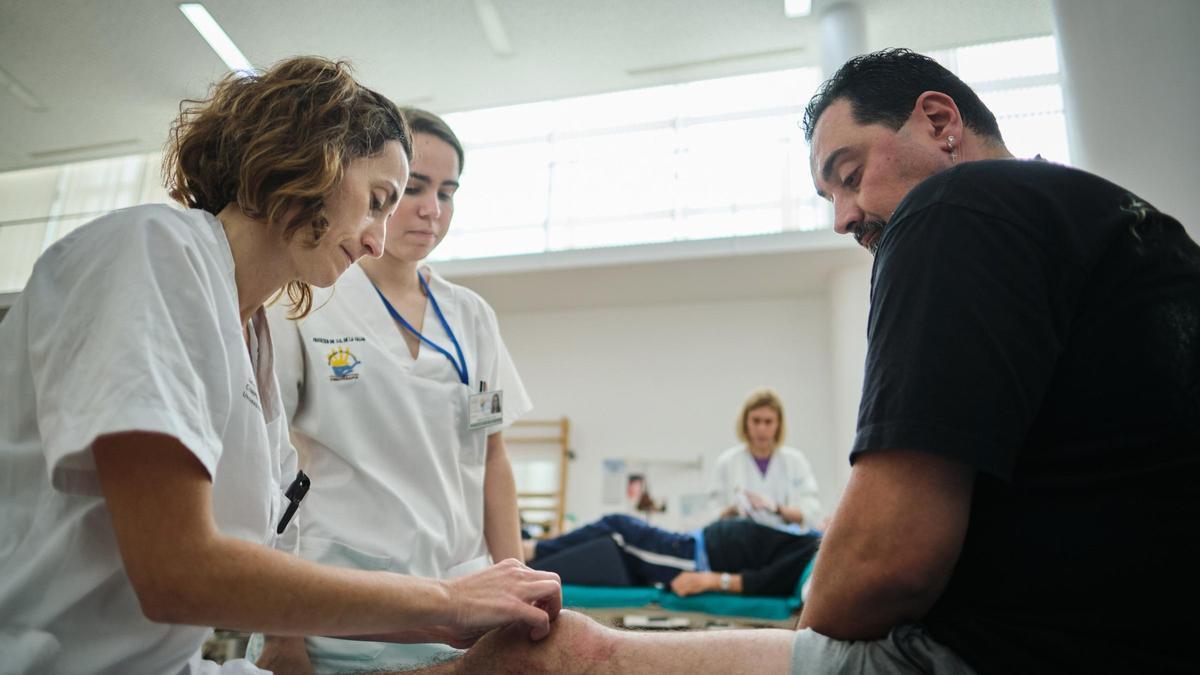 Dos fisioterapeutas tratan a un paciente en el Hospital Universitario de Canarias.