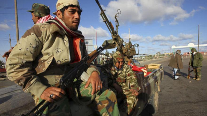 Miembros armados de las fuerzas rebeldes toman posiciones junto a una batería antiaérea cerca de Ras Lanuf.