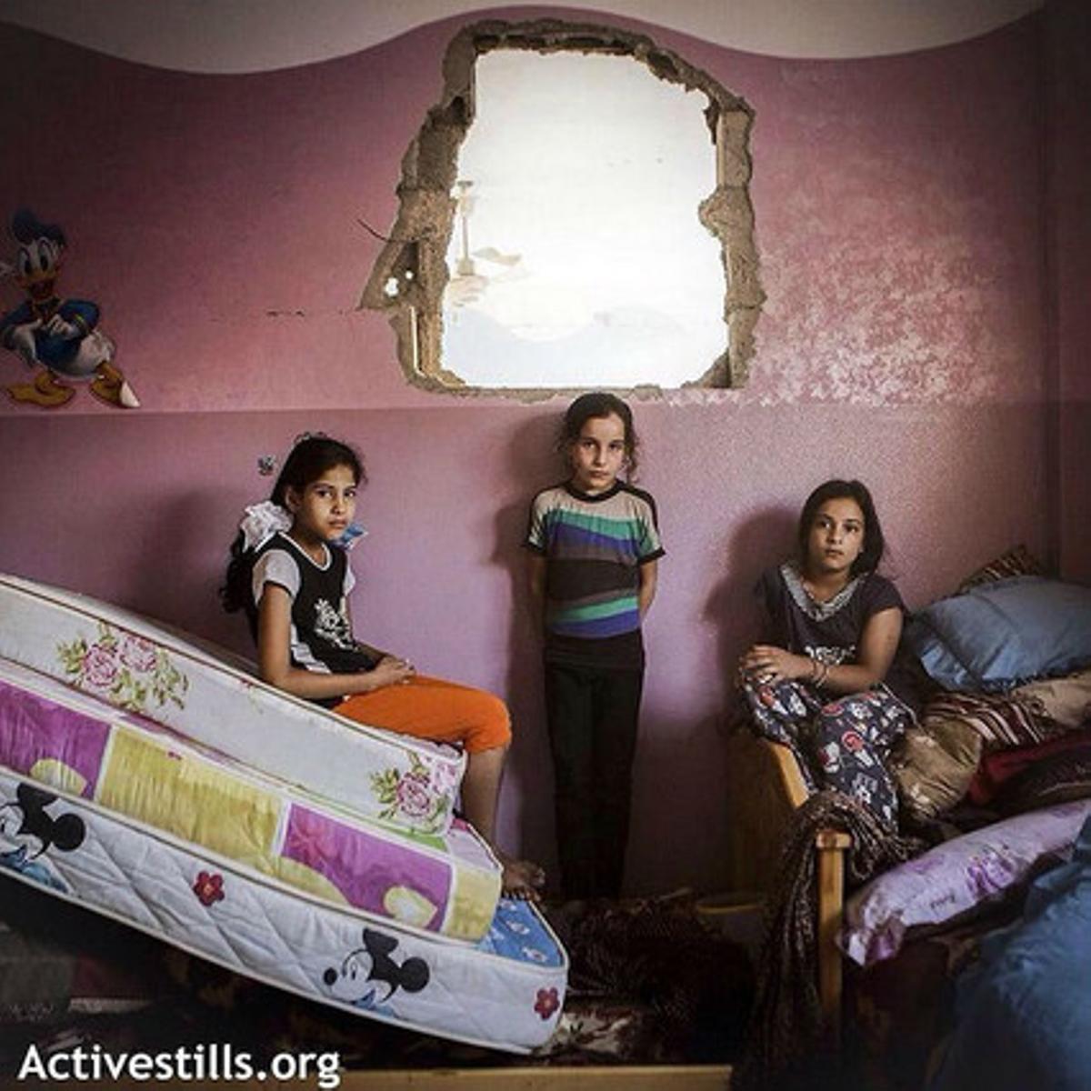 Tres nenes, entre els matalassos de la seva habitació.