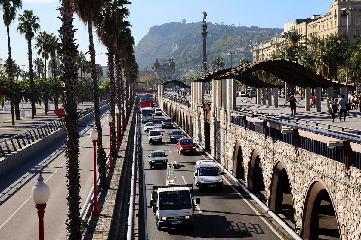 Coches pasando por la Ronda Litoral a su paso en el puente del Moll de la Fusta, con Colom de fondo.