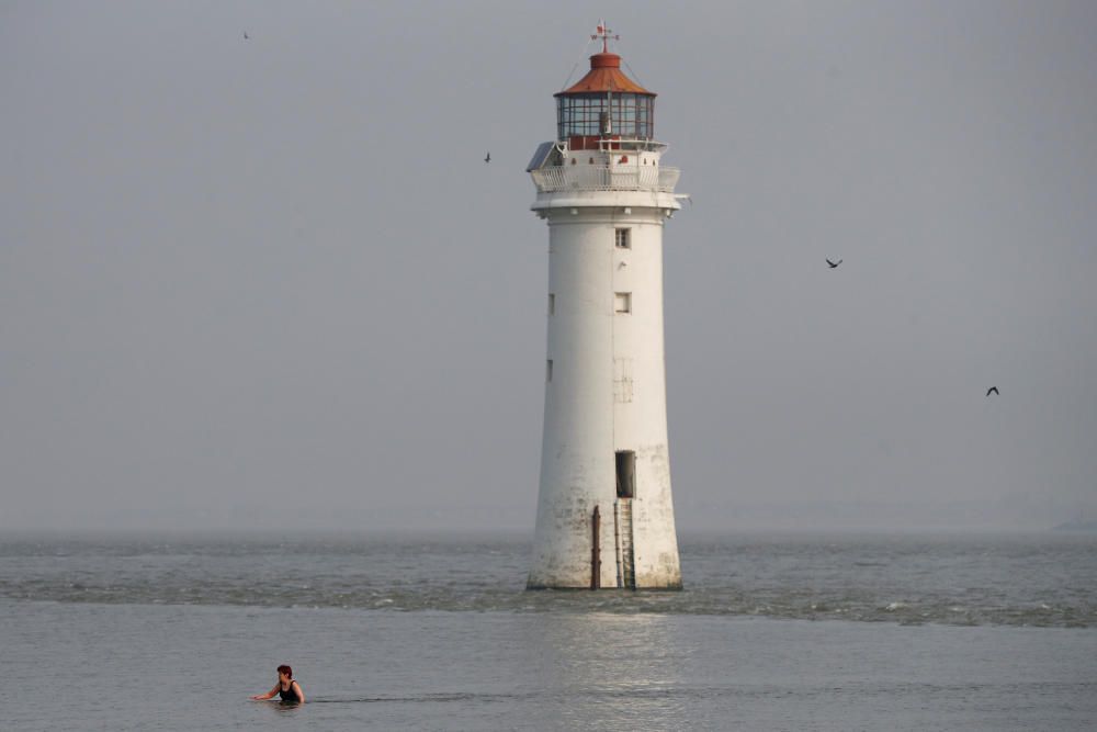 A woman swims in the sea in front of Perch Rock ...