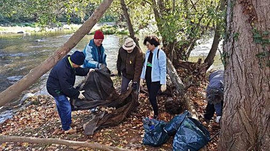 Un grup de voluntaris recull residus a la vora del riu Ter.