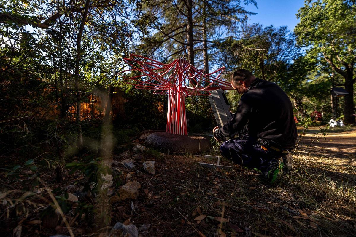Un operario instala una de las figuras de luz del espectáculo de Natura Encesa, en los jardines de Torre Girona, en Barcelona.