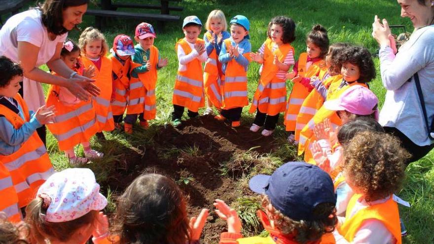 Los escolares de 3 años aplauden tras plantar un roble.