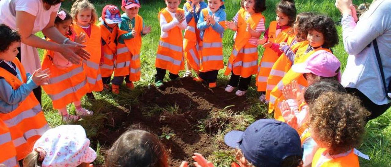 Los escolares de 3 años aplauden tras plantar un roble.