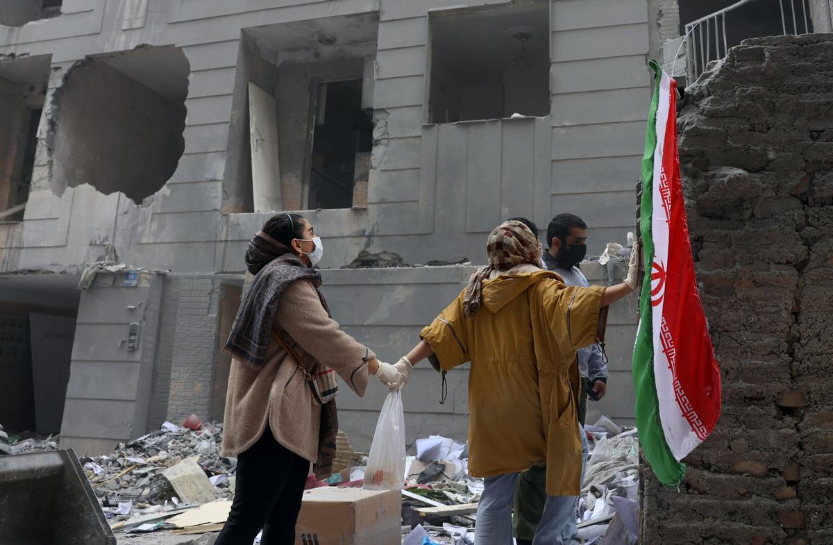 TEHRAN (Iran (Islamic Republic Of)), 15/03/2026.- Iranian sisters hold hands as they stand in front of their damaged residential building in southern Tehran, Iran, 15 March 2026. A joint Israeli and US military operation continues to target multiple locations across Iran since the early hours of 28 February 2026. (Teherán) EFE/EPA/ABEDIN TAHERKENAREH