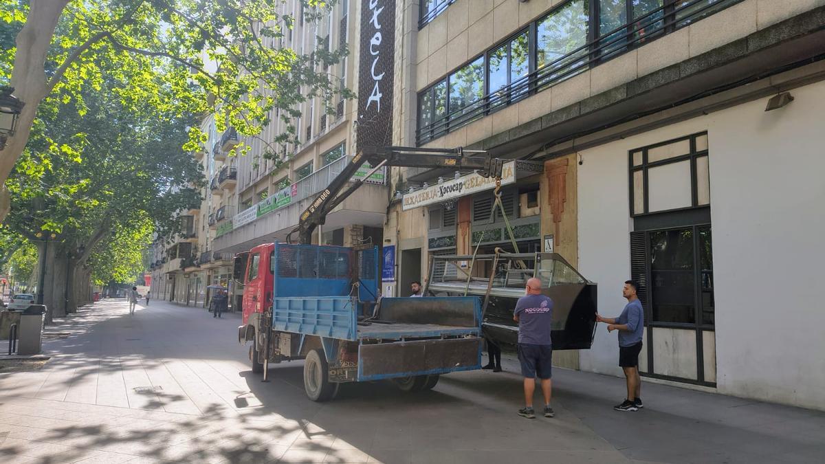 Un grupo de operarios traslada uno de los grandes mostradores que había en la horchatería, ayer.