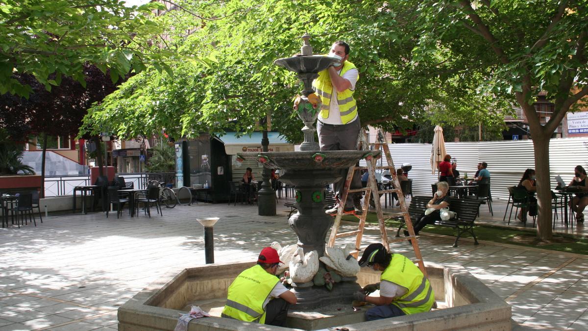 Alumnos del taller de Pintura decorativa lijando la fuente de San Vicente.