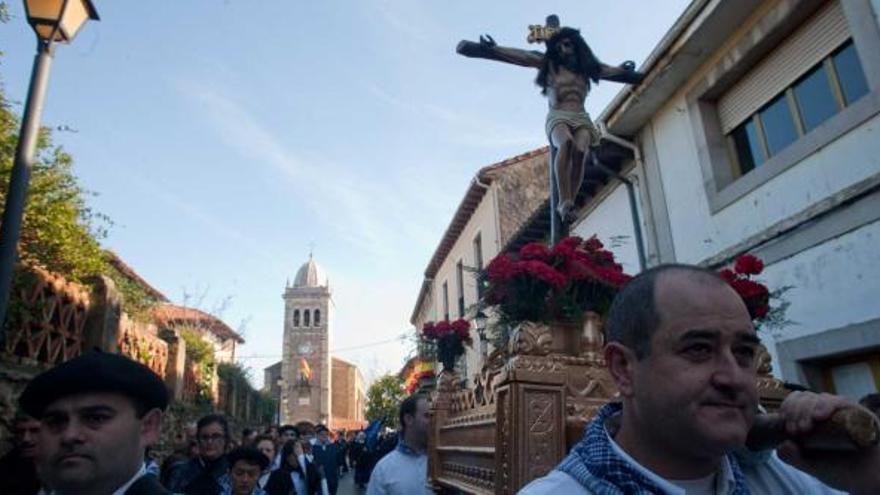 Los costaleros portan al Cristo del Socorro, con la iglesia de Santa María de Luanco, al fondo.