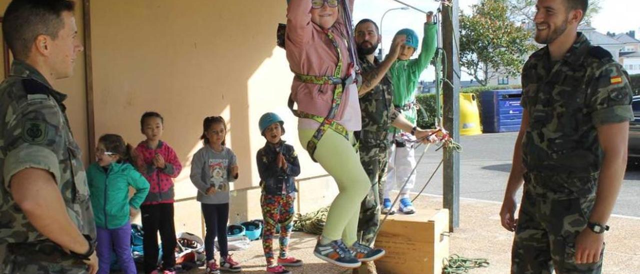 Abril García realiza uno de los ejercicios de escalada. A la derecha, un militar enseña a ponerse el casco a la alumna Fang Yi Zhou.