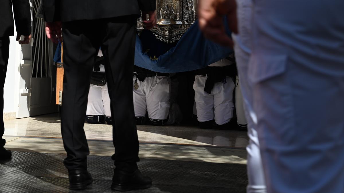 Costaleros de la Virgen de rodillas, para sacar el paso de la iglesia.