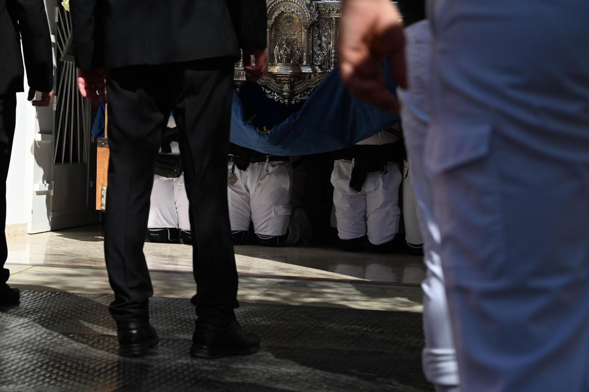 Costaleros de la Virgen de rodillas, para sacar el paso de la iglesia.