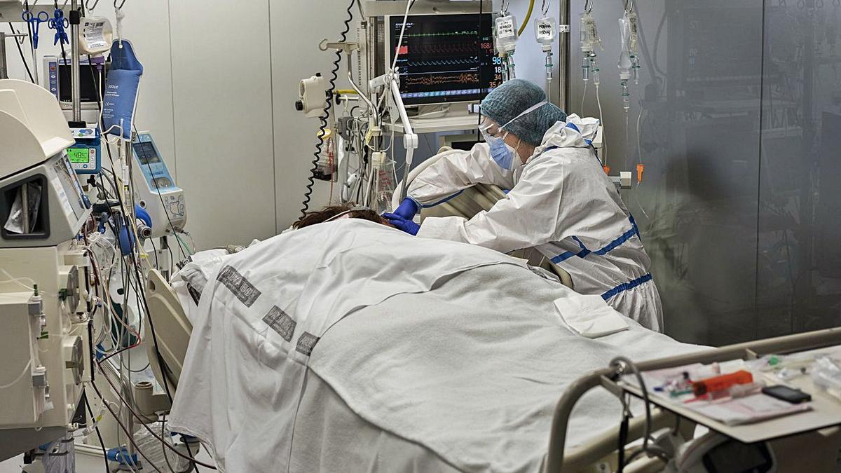 Una sanitaria atiende a un paciente covid-19 en la UCI del Hospital General de València. | G. CABALLERO