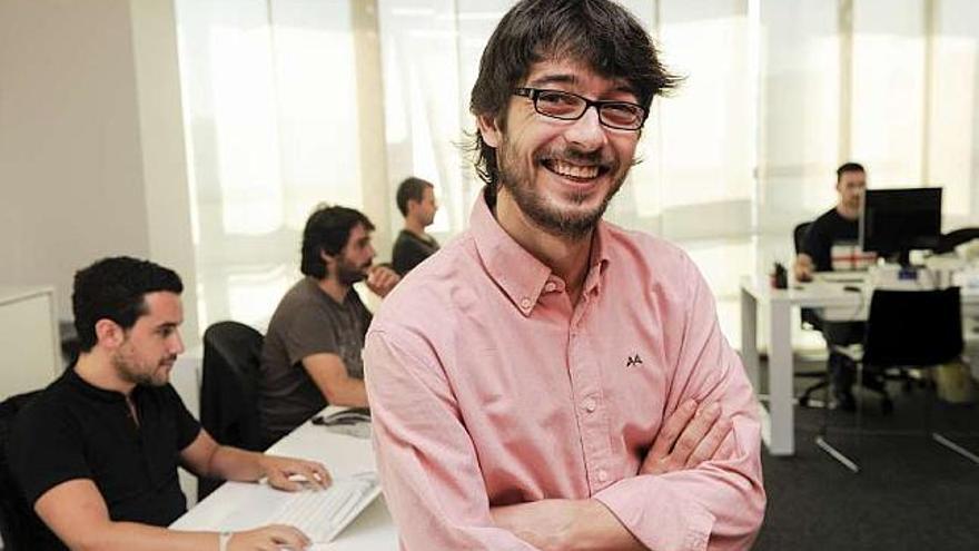 David Bello posa en su empresa con su equipo de programadores detrás. / fran martínez