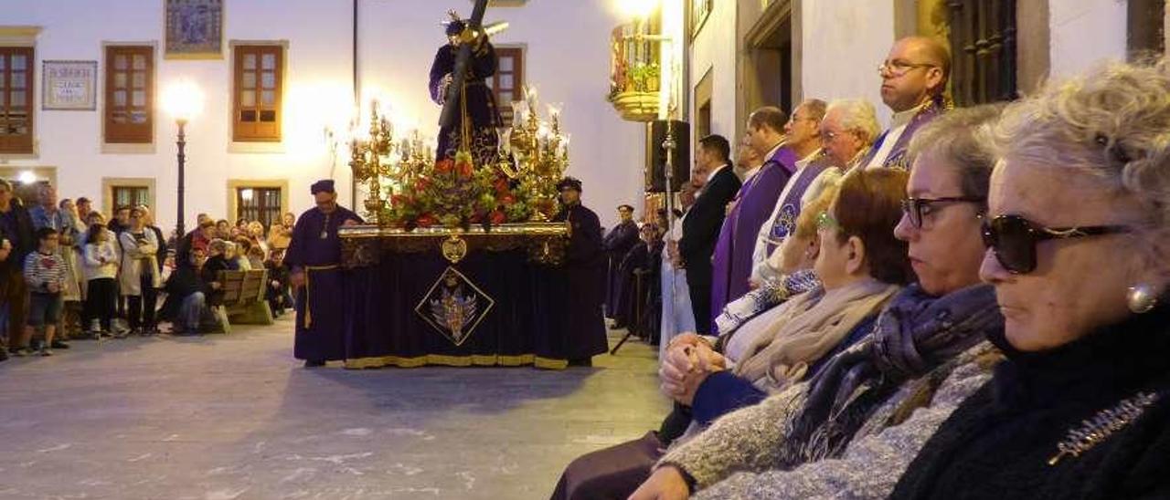 Un grupo de mujeres porta velas frente a un paso infantil.