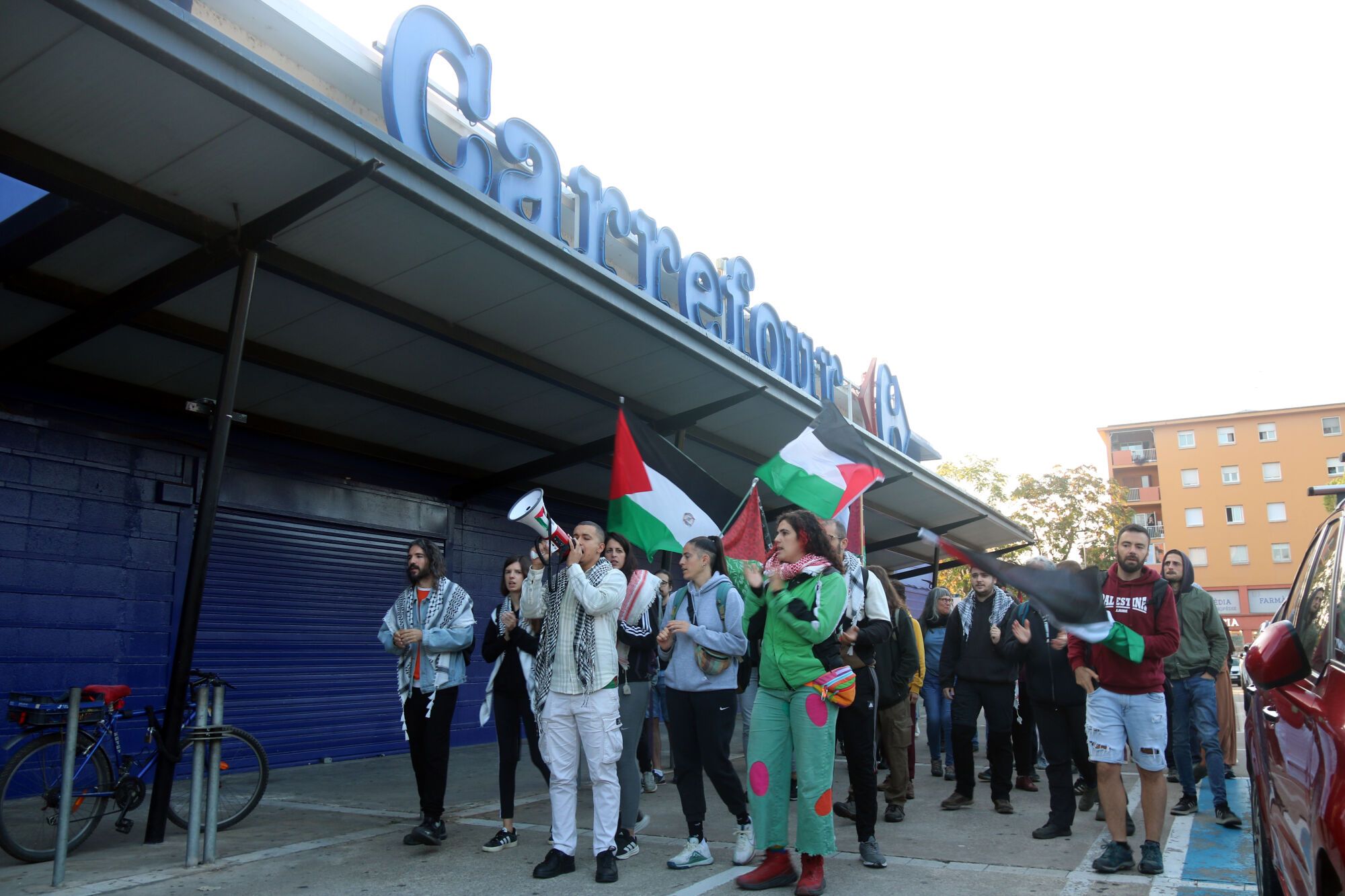 Els manifestants passant per davant del rètol de Carrefour de Girona