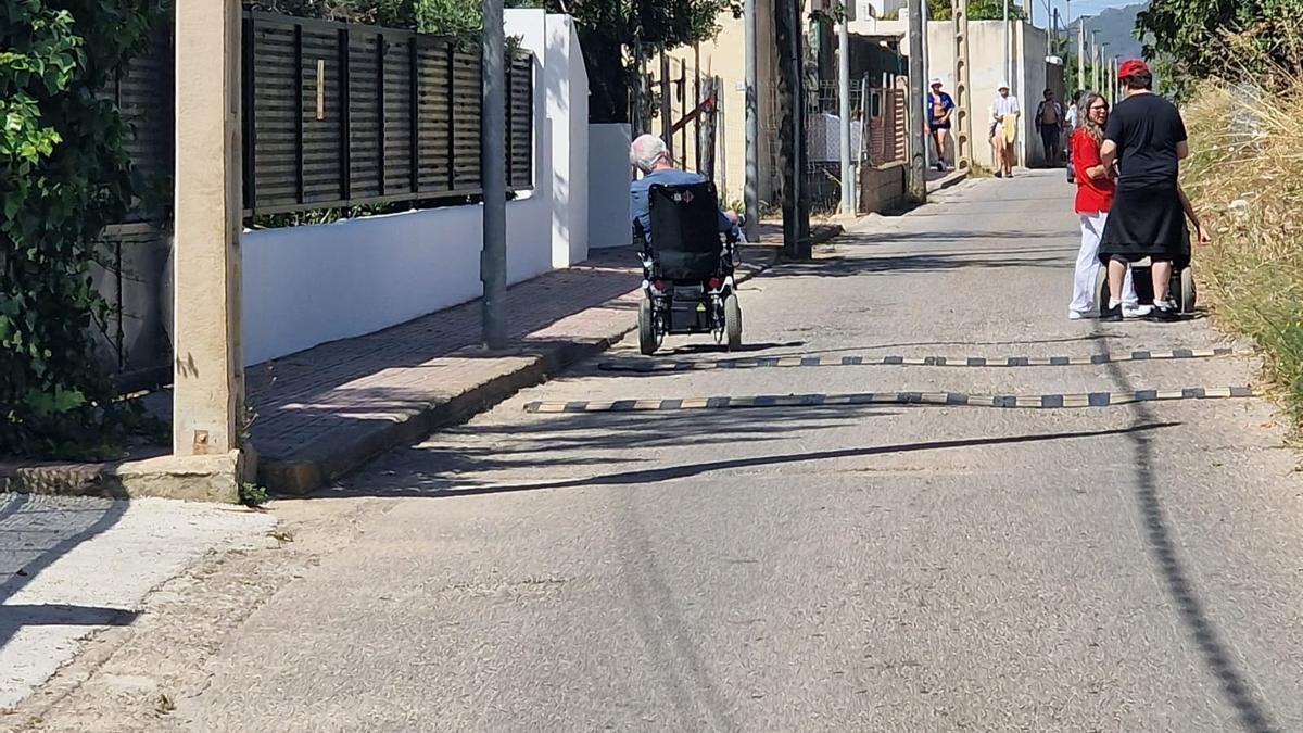 Un hombre en silla de ruedas por la calzada en la calle de la Mèrlera.