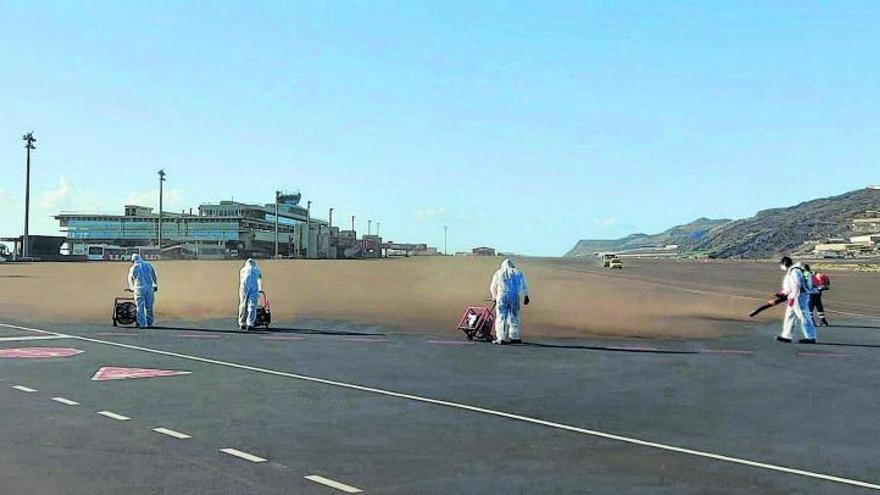 Operarios del aeropuerto de La Palma limpiaron el sabado la ceniza que se había acumulado en la pista.e | | E. D.