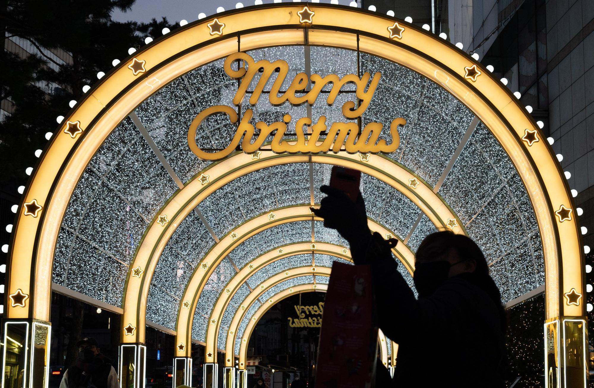 Seúl (República de Corea), 17/12/2021.- Una mujer se toma un selfie con adornos navideños iluminados en Seúl, Corea del Sur, 17 de diciembre de 2021. (Corea del Sur, Seúl)