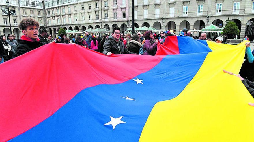 Un grupo de venezolanos extiende la bandera de su país en la plaza de María Pita.  // Víctor Echave