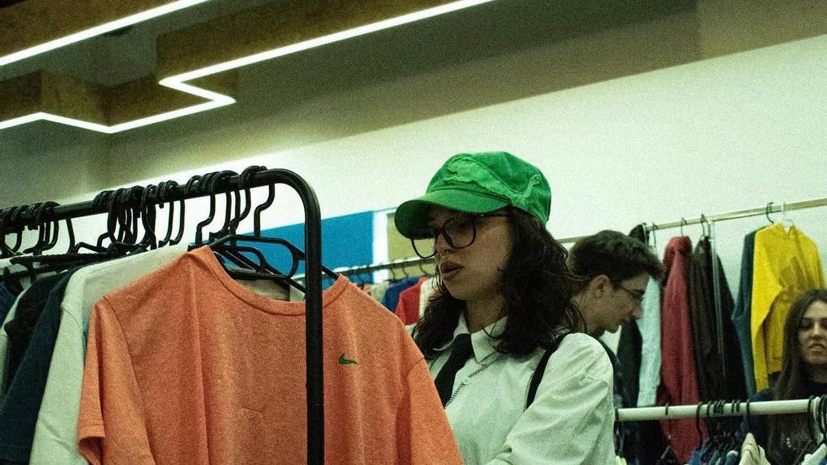 Una mujer mira la ropa en el mercado vintage.