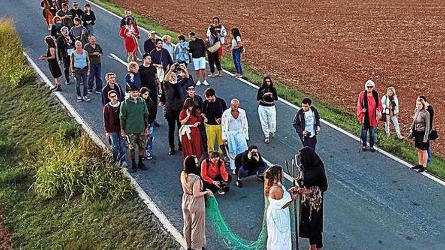 Un momento de la procesión de artistas en la carretera del Pilar de la Mola al faro donde siguieron por la tarde más actuaciones.