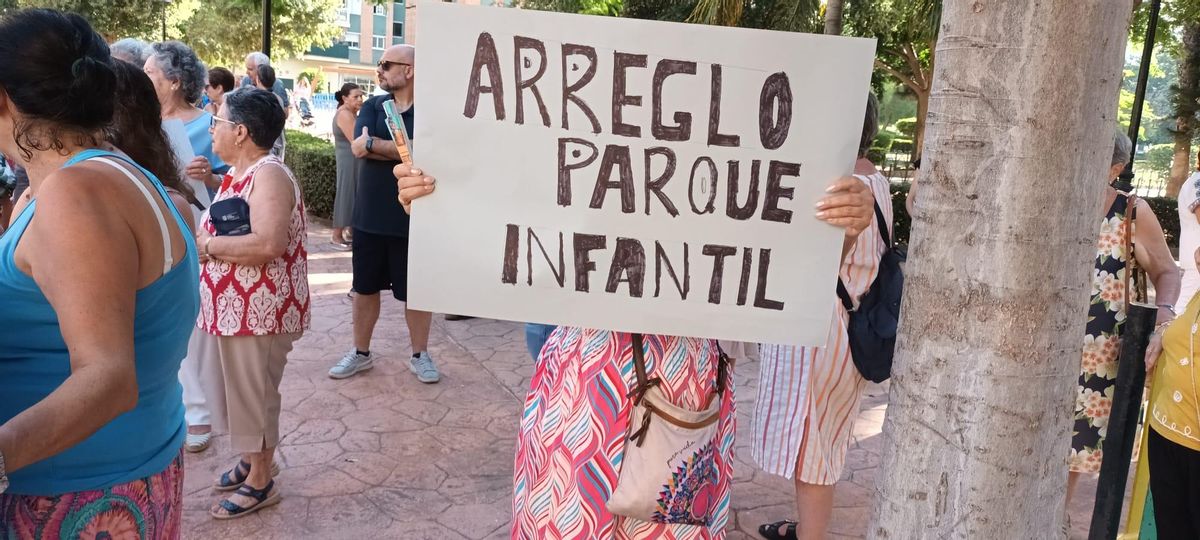 Una vecina, con un cartel que exige el arreglo del parque infantil del barrio