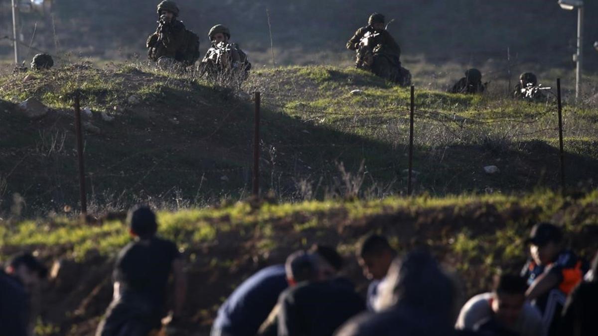Soldados israelís y civiles palestinos, separaldos por la valla de seguridad cerca de Nablús, en Cisjordania.