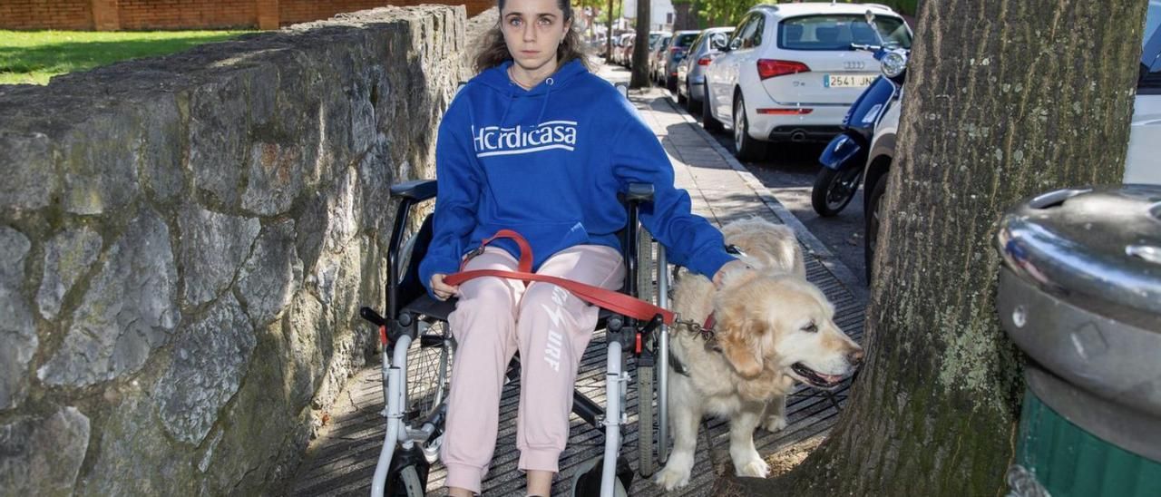 Carmen López, con su perra &quot;Luna&quot;, en una acera de Ciudad Naranco limitada por un árbol y una papelera.