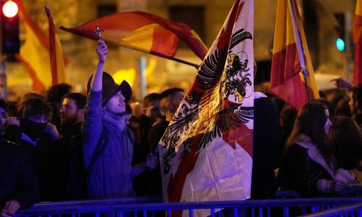 Un manifestante con la cruz de Borgoña ante el cordón policial de la calle Ferraz de Madrd