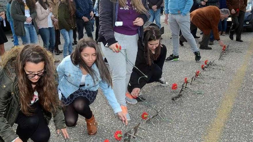 Unas jóvenes colocan flores en la inscripción. // Rafa Vázquez