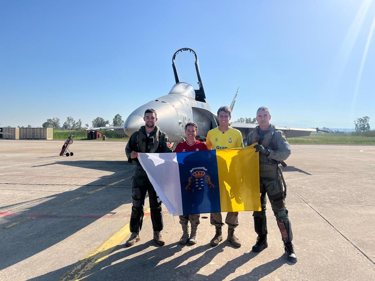 Ramírez, a la derecha, junto a otros compañeros, mostrando una bandera canaria en la base aérea de Grecia