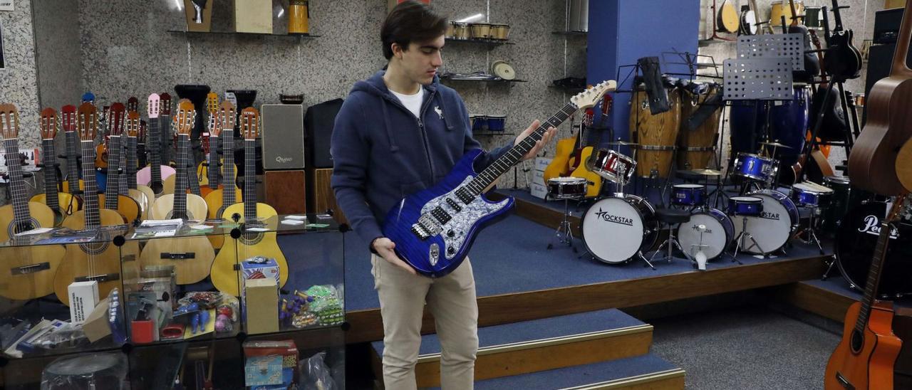 Mauro, empleado de Centromúsica, con una guitarra eléctrica que está a la venta en esta tienda de instrumentos de València.