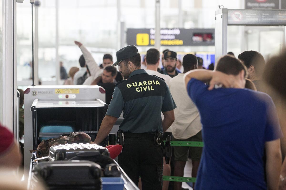 Colas en un aeropuerto valenciano pasando el control con las maletas.