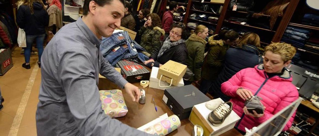 Un comerciante atiende a una clienta en un establecimiento de Mieres.