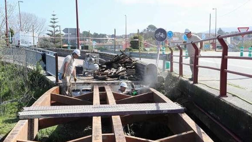 Operarios en el paseo de madera cerrado por reformas. // R. Grobas