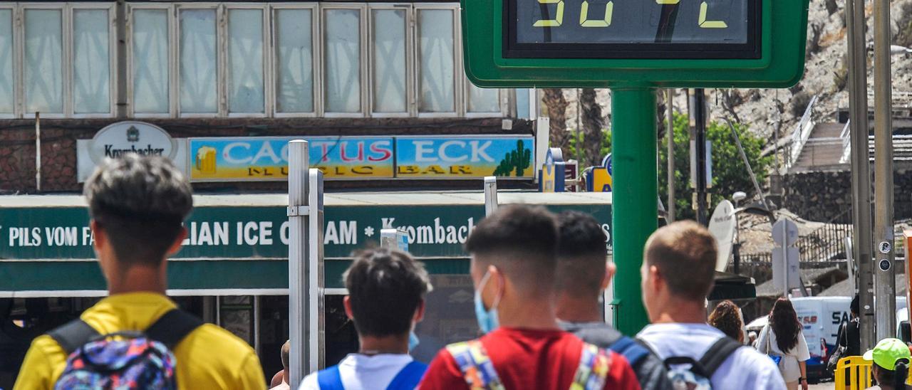 Unos jóvenes pasean en Gran Canaria, bajo un termómetro que marca 30 grados. | | JUAN CARLOS CASTRO